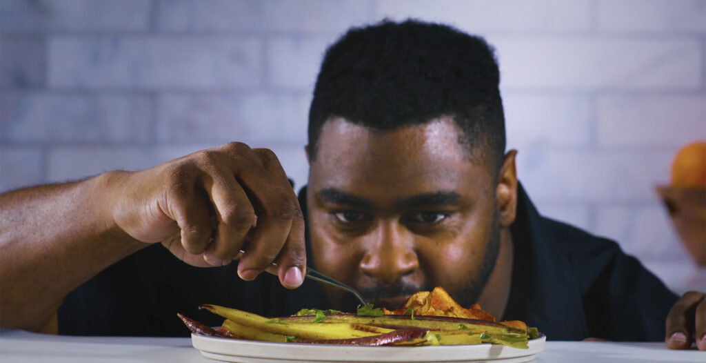 A man in a kitchen preparing a dish 